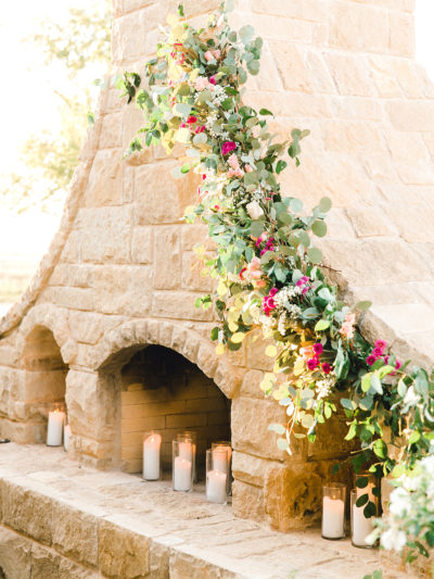 Backyard wedding with flower garland on fireplace. 